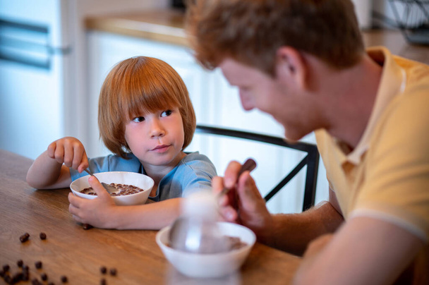 Breakfast together. Dad and son sitting at the table and eating breakfast - 写真・画像
