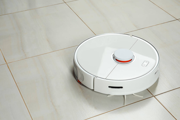 Robotic vacuum cleaner on white tiled floor, space for text - Foto, Imagem