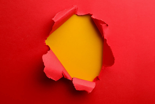Hole in red paper on yellow background - Fotografie, Obrázek