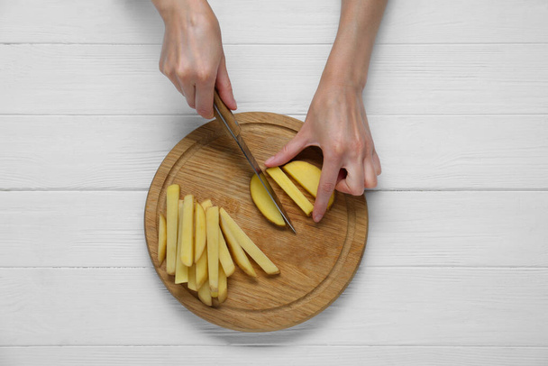 Woman cut potatoes on white wooden table, top view - Фото, изображение