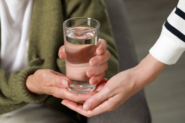 Caregiver giving water to elderly woman at home, closeup - Valokuva, kuva