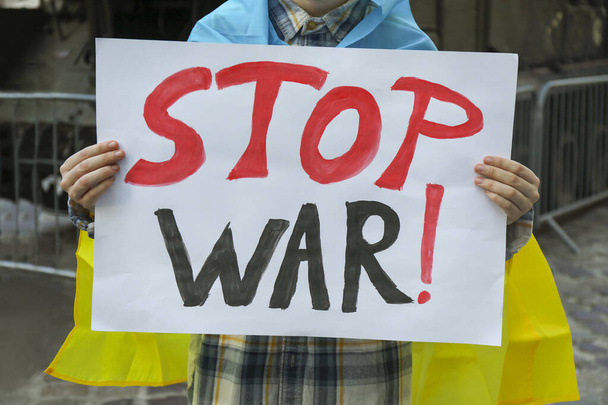Woman wrapped in Ukrainian flag holding poster with words Stop War outdoors, closeup - Foto, afbeelding