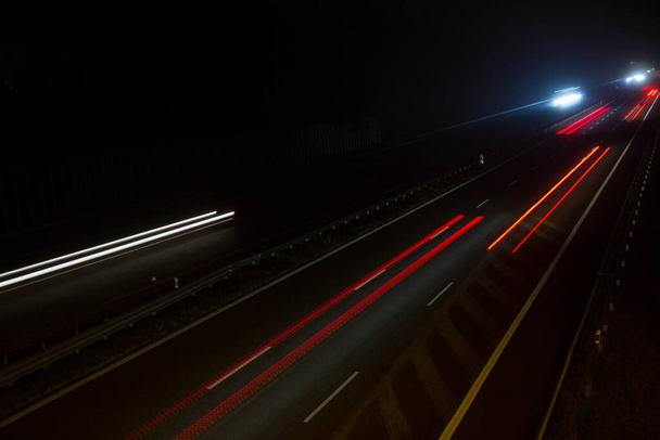 Auto lichte paden 's nachts op een snelweg gezien naar beneden, lange blootstelling  - Foto, afbeelding