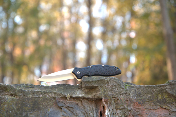 折りたたみナイフ美しいデザインシルバーブレード黒ハンドル屋外自然グレー石マクロの背景 - 写真・画像