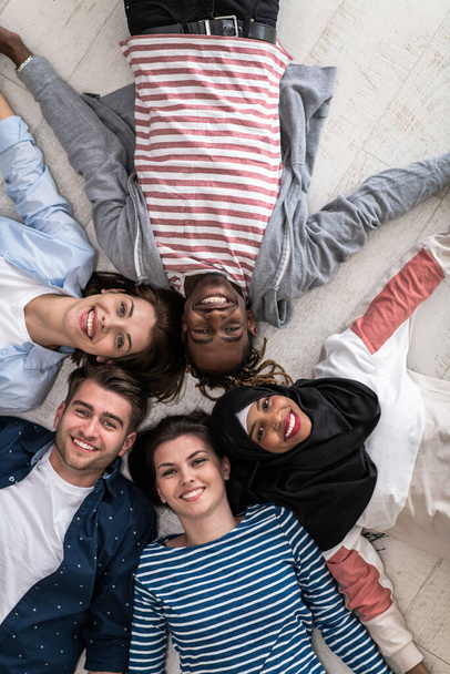 Top view of a diverse group of people lying on the floor symbolizes togetherness. High quality photo - Фото, зображення