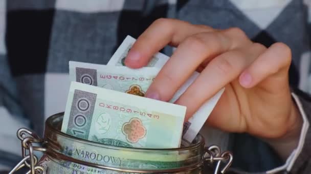 Polish zloty banknote saving money in glass jar. Unrecognizable woman moderate consumption and economy Collecting money. Tips. Business, finance, saving, banking and people concept. Extra money - Кадри, відео
