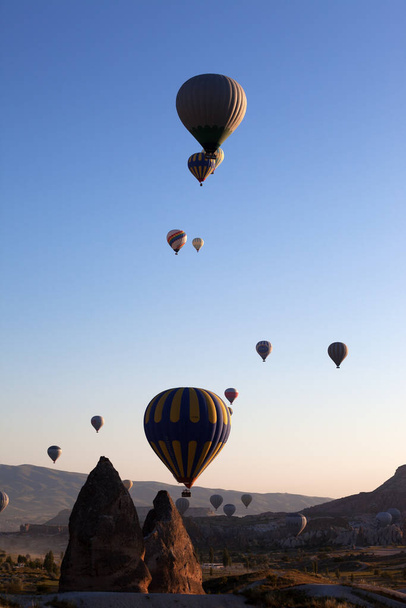 GOREM, CAPPADOCIA, TURKEY - MAY, 2013: Hot air balloons on blue clear sunlight sky and fairy chimneys rock formations at early morning - Foto, Imagen