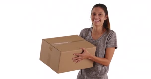Veselá mladá žena házející lepenkovou krabici do vzduchu na bílém pozadí s kopírovacím prostorem. Hezká běloška drží přepravní box se smíchem a dívá se do kamery ve studiu. 4k - Záběry, video