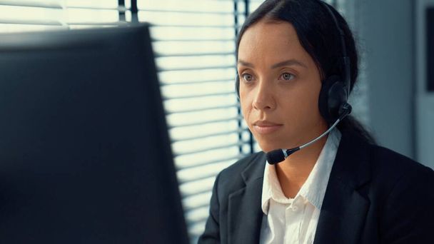 Competent female operator working on computer and talking with clients. Concept relevant to both call centers and customer service offices. - Foto, immagini