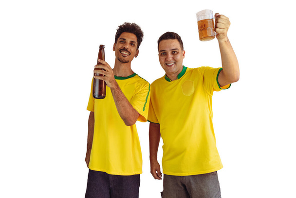 Czarni Bracia z żółtą brazylijską koszulą i butelką piwa pocieszające izolaty na białym. Kibice piłki nożnej dopingować Brazylię być mistrzem. - Zdjęcie, obraz