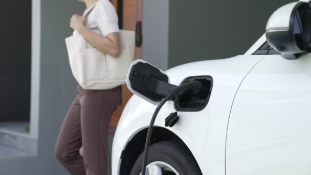 Žena odpojí nabíječku elektrických vozidel v jeho domě. Koncepce používání elektrických vozidel v progresivním životním stylu přispívá k čistému a zdravému prostředí. - Záběry, video