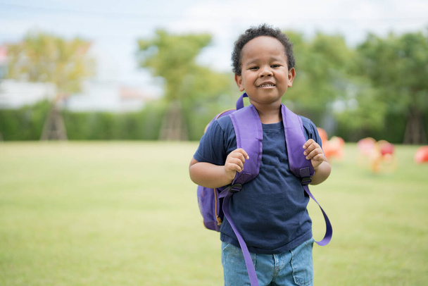 Симпатичний маленький хлопчик, що носить шкільну сумку з усміхненим обличчям, чекає, щоб піти додому
. - Фото, зображення