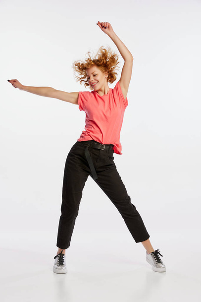 Happiness, music. Excited beautiful young redheaded woman dancing isolated on white studio background. Human emotions, facial expression, beauty concept. Copy space for ad - Foto, afbeelding