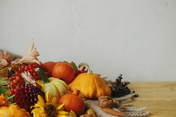 Autumn still life. Stylish pumpkins, autumn flowers, berries and nuts on rustic wooden table. Seasons greeting card template with space for text. Harvest at farm. Hello Fall - Photo, Image