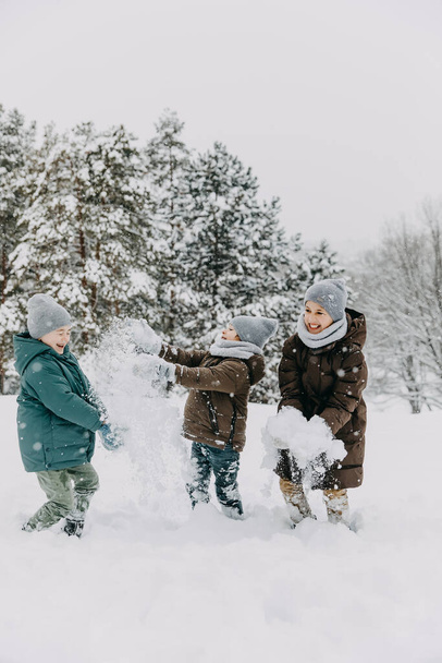 Children playing outdoors on winter day, laughing and throwing snow at each other. - Photo, Image
