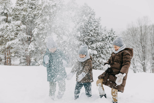 Jongens spelen buiten op winterdag, lachen en gooien sneeuw in de lucht. - Foto, afbeelding