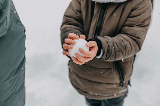 Closeup of a boy holding a snowball in bare hands. - Фото, изображение