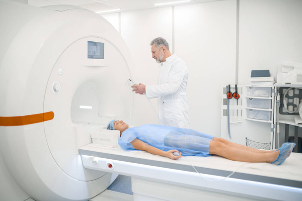 MRI. Mannelijke doagnostische specialist bereidt de patiënt voor op MRI - Foto, afbeelding