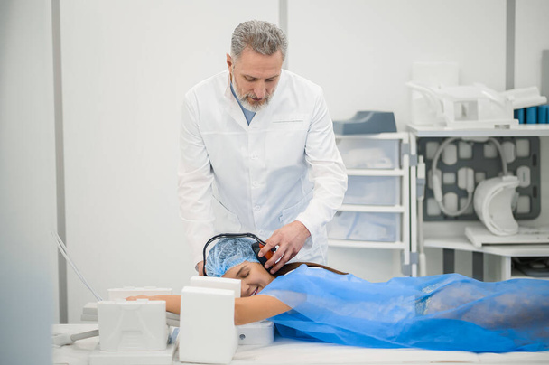 Diagnostik. Reifer männlicher Arzt bereitet Patientin auf MRT-Untersuchung vor - Foto, Bild