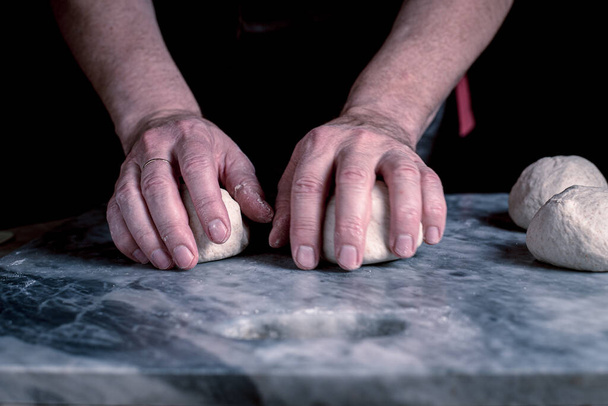 Ο άνθρωπος ετοιμάζει πίτσα, ζύμη σε μαρμάρινο τραπέζι. - Φωτογραφία, εικόνα
