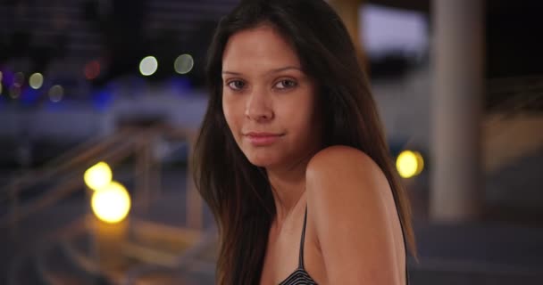 Close-up of beautiful Caucasian girl looking over her shoulder at camera. Portrait of young and attractive female in her 20s downtown in evening. 4k - Footage, Video