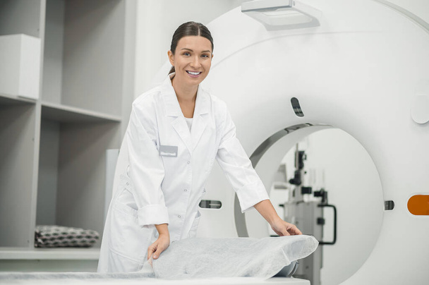 Before procedrure. Long-haired doctor preparing MRI scanner for work - Fotó, kép