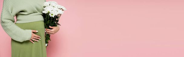 Cropped view of pregnant woman holding bouquet of white flowers isolated on pink, banner  - Photo, Image