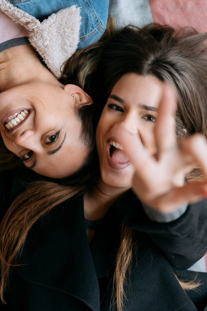 Young lesbian couple in love happily lying on the floor looking at camera smiling - Foto, Imagen