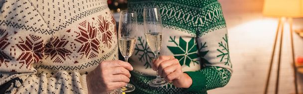 vue recadrée du couple d'âge moyen en chandails festifs cliquetis verres de champagne, bannière - Photo, image