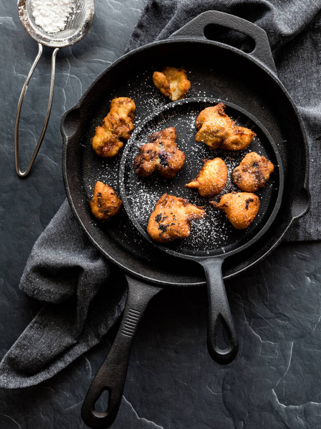 Top down view of fry pans filled with deep fried blueberry fritters, topped with powdered sugar. - Foto, imagen