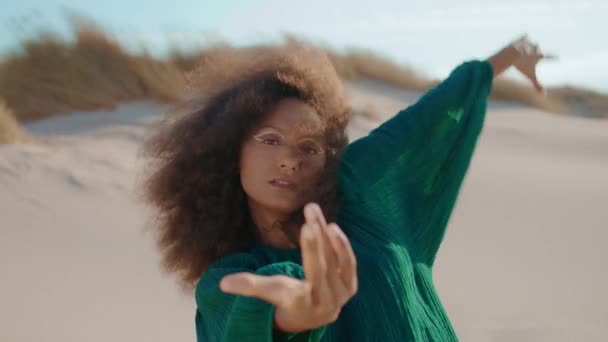 Mulher afro-americana flexível dançando improvisação em dunas de areia close-up. Curly jovem dançarina morena dobra corpo se movendo sedutoramente. Menina encaracolado atraente realizando vestindo vestido preto no deserto - Filmagem, Vídeo