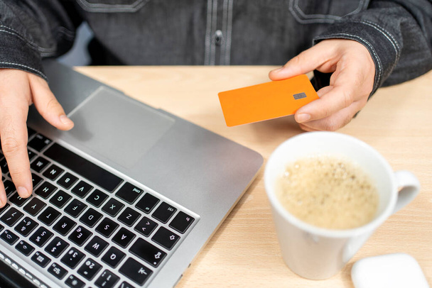 Mann bezahlt mit Kreditkarte und Laptop am Schreibtisch - Foto, Bild