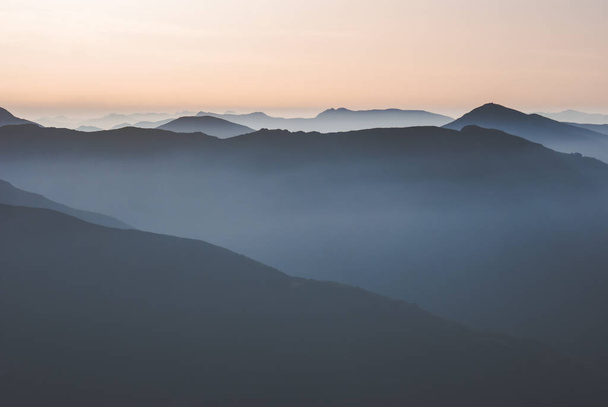 Ομίχλη κυλάει πάνω από τα βουνά των Λος Ανχέγιες την αυγή. Βόρεια της Ισπανίας. - Φωτογραφία, εικόνα