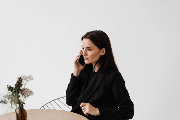 Beyaz kafede telefonla konuşan çekici bir kız. Akıllı telefon kullanan aile ve arkadaşlarla iletişim - Fotoğraf, Görsel