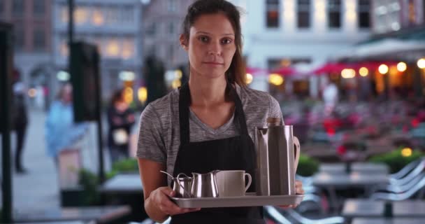 Poważna kelnerka niosąca tacę z kawą i herbatą w zewnętrznej kawiarni turystycznej. Portret nieszczęśliwej atrakcyjnej baristki trzymającej tacę do serwowania. 4k - Materiał filmowy, wideo