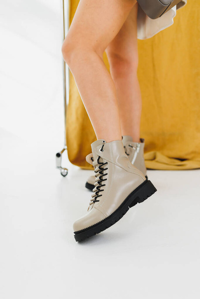 Women's leather shoes. Female legs in beige leather boots. Fashionable women's boots. - Фото, зображення