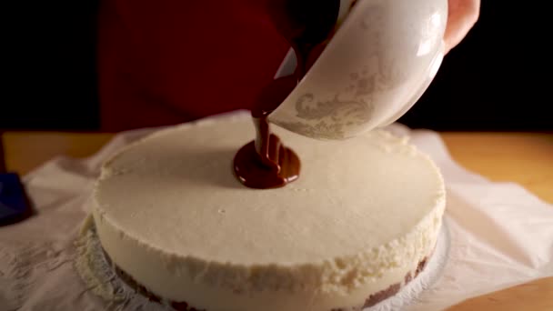 Movimiento lento de un chocolate derretido oscuro vertiendo sobre una superficie de un pastel de leche de coco, deliciosa preparación de la torta. - Metraje, vídeo