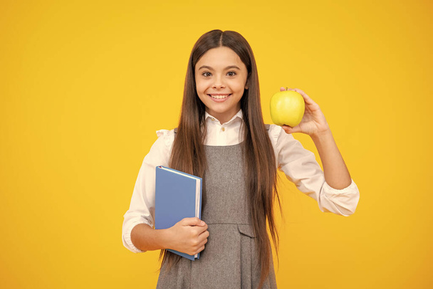 Школярка, студентка-підліток, тримає книгу на жовтому ізольованому студійному фоні. Шкільна та освітня концепція. Назад до школи
 - Фото, зображення