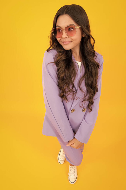 Повна довжина веселого дівчинки-підлітка в одязі відповідає модному одягу, ізольованому на жовтому тлі
 - Фото, зображення