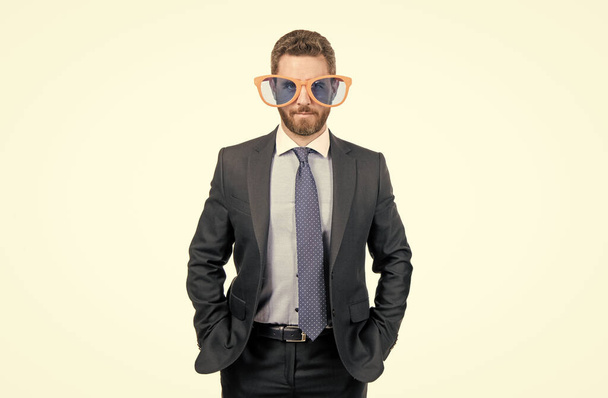 Serieuze man zakenman in formele pak en grappige bril staan hand in hand in zakken geïsoleerd op witte, corporate partij. - Foto, afbeelding