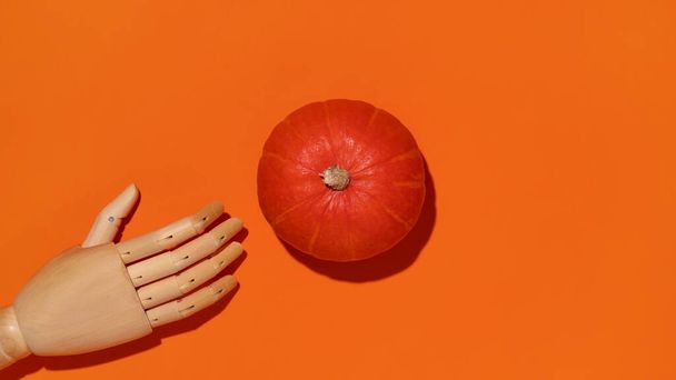 Calabaza naranja y mano de madera sobre fondo naranja. Foto de alta calidad - Foto, imagen