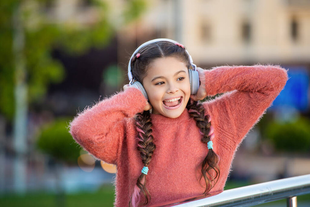 Happy girl singing to music. Melomaniac girl singing song outdoors. Teen girl wear headphones while singing. - Фото, зображення