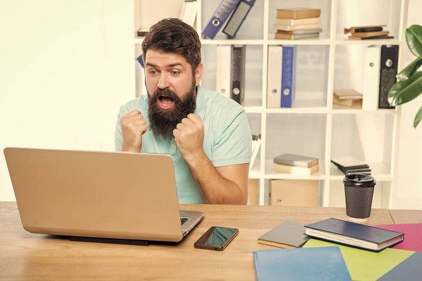 Excited businessman making fists looking in laptop at office desk, anticipation. - Photo, image
