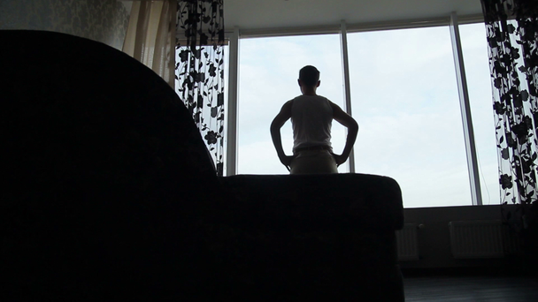 Σιλουέτα του ανθρώπου που ψάχνει έξω από το παράθυρο στην επίπεδη - Πλάνα, βίντεο
