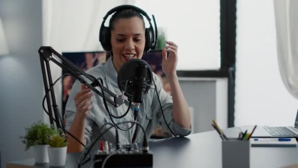 Creative podcaster hosting internet live talk show while sitting in studio. Popular influencer discussing last news with audience while wearing headphones and using professional microphone. - Séquence, vidéo