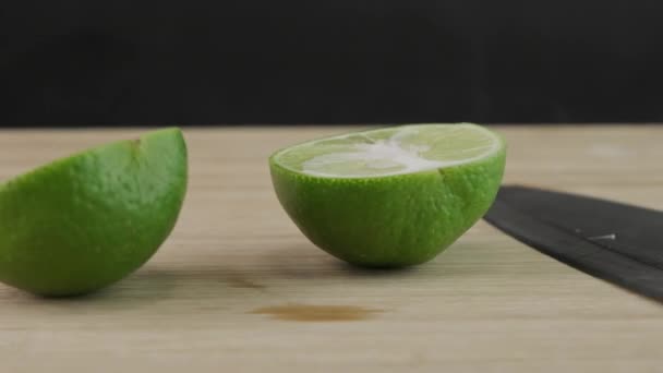 Tagliare a mano il limone a metà con coltello su tagliere in legno in cucina. Affettato frutta fresca di lime con coltello da vicino. - Filmati, video