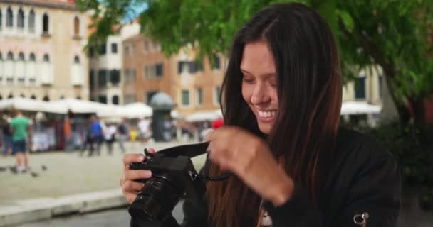 ヴェネツィアの通りで休暇中に写真を撮る100万人の女性の閉鎖。爆撃機のジャケットの幸せな旅行者は、有名なイタリアの都市の通りの写真を撮るためにカメラレンズに焦点を当てています。4k - 映像、動画