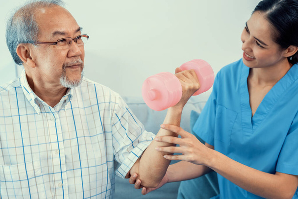 Contented senior patient doing physical therapy with the help of his caregiver. Senior physical therapy, physiotherapy treatment, nursing home for the elderly - Foto, immagini