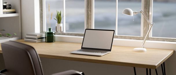 Minimal design degli interni degli spazi di lavoro scandinavi con mockup per laptop, lampada da tavolo e arredamento su tavolo in legno contro la finestra. Rendering 3d, illustrazione 3d - Foto, immagini