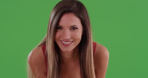 Pretty Millennial Frau lächelt und bläst Küsse in die Kamera auf Greenscreen. Glücklich lachendes kaukasisches Mädchen in ihren Zwanzigern mit Händen auf Knien, die Blickkontakt herstellen. 4k auf Grün zum Keying oder Compositing - Filmmaterial, Video